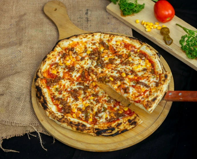 a pizza on a cutting board with a wooden spatula
